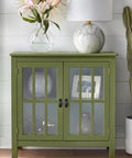 Green cabinet with glass doors, floral vase, lamp, and decorative items, adding style to modern interiors.