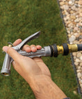 Hand holding brass quick disconnect garden hose fittings set with durable male and female connectors and rubber grips in use