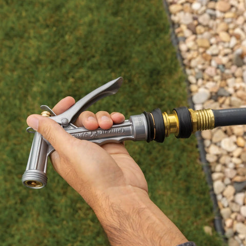 Hand holding brass quick disconnect garden hose fittings set with durable male and female connectors and rubber grips in use