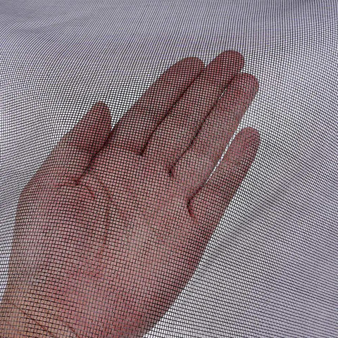 Hand touching fiberglass screen roll for windows and doors, high visibility flexible mesh for easy DIY repair and rescreen.