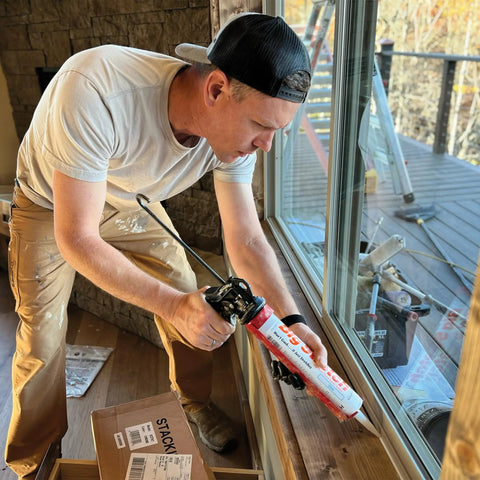 Person using DIY Ready Latex Caulk Sealant 12 Pack 10.5 Ounce Tubes Almond Color Ultra Flexible Indoor Outdoor Waterproof Gap Filler That Will Not Crack Or Shrink With Home Movement on window frame
