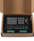 Front view of a DM556 microstep driver module in black enclosure with two green terminal blocks inside a cardboard box