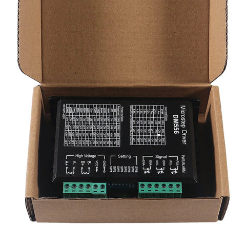 Front view of a DM556 microstep driver module in black enclosure with two green terminal blocks inside a cardboard box