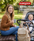 Woman with stroller and heavy duty stroller hooks for bags and gear, baby smiling, park setting, universal clips attached