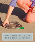 Person holding Heavy Duty Yet Lightweight Metal Garden Hose Lite 50 Ft Kink-Proof Stainless Steel Casing on pavement