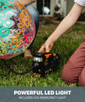 Person using Cordless Tire Inflator With Digital Gauge On The Go Portable Air Pump to inflate a colorful ball on grass