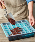 Person filling 36 Cell Reusable Seed Starter Tray For Easy Indoor Seed Starting Of Vegetables Flowers And Herbs With No Fuss Pop Out Cells