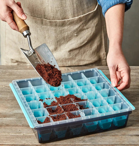 Person filling 36 Cell Reusable Seed Starter Tray For Easy Indoor Seed Starting Of Vegetables Flowers And Herbs With No Fuss Pop Out Cells