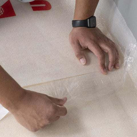 Top Shelf 100 Square Foot Laminate And Engineered Wood Flooring Underlayment Roll, hands unrolling heavy duty foam backing.