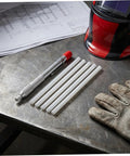 Soapstone Marking Pencil With Aluminum Holder For Welding Supplies on metal table with gloves and welding helmet nearby.
