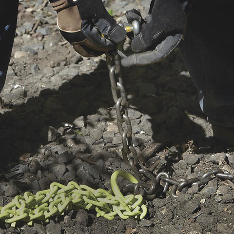Close-up of Heavy Duty Triple Chain Shrub And Clump Remover Tool on rocky ground, showing chain details and connection.
