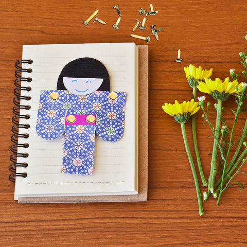 500 Piece Mini Brass Paper Fasteners Gold Pin Backs with paper doll on notebook and yellow flowers for crafting.