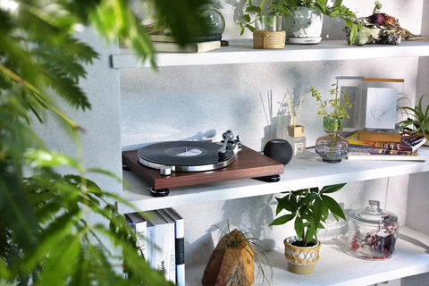 Audio-Technica At-Lpw50bt-Rw Manual Belt-Drive Turntable In Slick Rosewood With Bluetooth Wireless Tech on a shelf with plants.