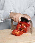 Front view of Fox Run stainless steel crinkle cutter with black handle slicing red bell pepper.