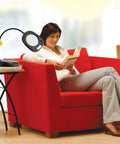 Woman reading next to Go-To LED Floor Lamp And Table Lamp With 5-Inch Magnifier on side table in living room setting.