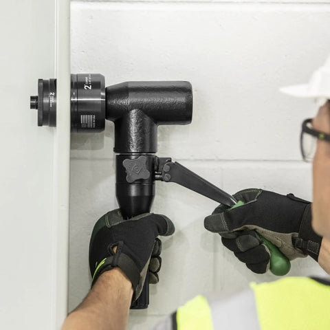 Person using Heavy Duty Hydraulic Knockout Kit with Quick Draw Driver for precise 2-inch hole in metal wall.