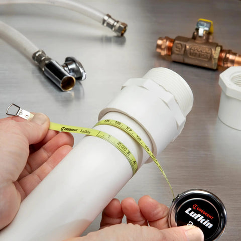 Diameter Measuring Pocket Sized Tape Measure 6mm By 2m Dual Sided Blade measuring a white pipe on metallic surface