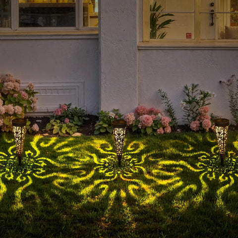 Solar Powered Fire Totem Style Outdoor Garden Lights Six Pack Waterproof Conical Stakes illuminating a garden at night