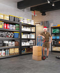 Man with hand truck in front of Beefy Heavy Duty Metal Garage Shelving Unit with Thick Steel Frame and MDF Shelves, garage setting