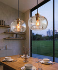 CASAMOTION Glass Pendant Lights, Textured Clear Globe Shade illuminating a dining table with a modern design.