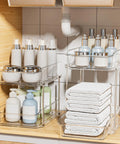 Slick Clear Under Sink Organizers And Storage Bins 2 Pack With High Low Design For Bathroom Cabinet Decluttering Pantry Organization showing toiletries and towels.