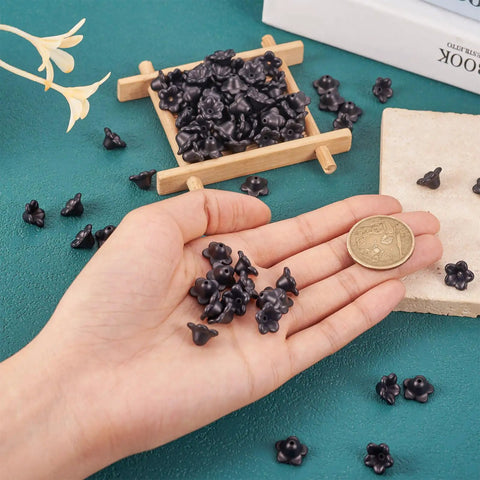 Black Acrylic Flower Bead Caps 100 Pcs Five Petal Frosted Resin Flower Spacers in hand on green surface