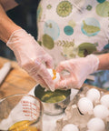 Person using Heavy Duty Clear Vinyl Work Gloves Three Mil Thick Box Of One Hundred Xlarge Latex Free And Powder Free while cracking eggs.