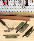 Four Pack Antique Bronze Folding Butt Hinges Measuring 2.5 By 1.69 Inches For Cabinet Doors Rustic Windows Wood Boxes And Heavy Duty Vintage Brass Finish Furniture Hardware That Is Badass Rust Resistant And Gonna Work Sweet For Yall with hammer and screws on workbench.