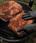 Grill Ready Disposable BBQ Gloves Kit With 50 Nitrile Gloves, handling meat on a grill, showcasing heat resistance and protection.