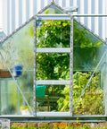 Glass greenhouse in garden setting with visible aluminum frame and greenery inside, showcasing greenhouse application.