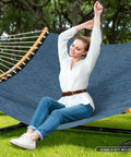 Woman sitting on two person hammock with heavy duty curved bar for poolside and backyard lounging. Navy Textilene and Olefin fabric.