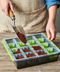 SuperSeed All In One Seed Starting Tray With 16 XL Cells being filled with soil using a trowel on a wooden table