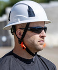 Worker wearing tinted safety glasses from 12 pack ANSI Z87 Plus UV Eye Protection for construction, outdoor work, industrial safety.
