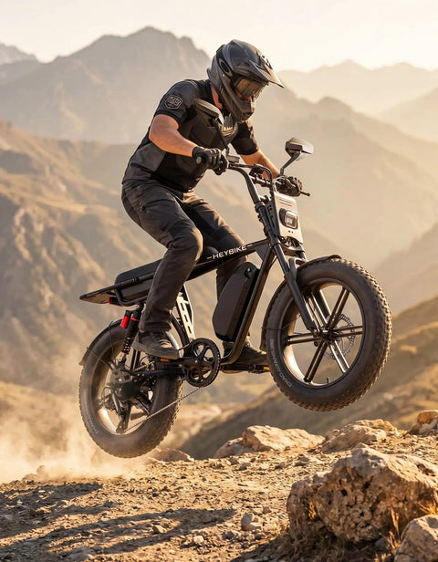 Dual Battery Adult Electric Bike With 956 Wh Juice And A Mean 1800W Motor Logging Ninety Miles on rocky terrain, rider in mid-jump.