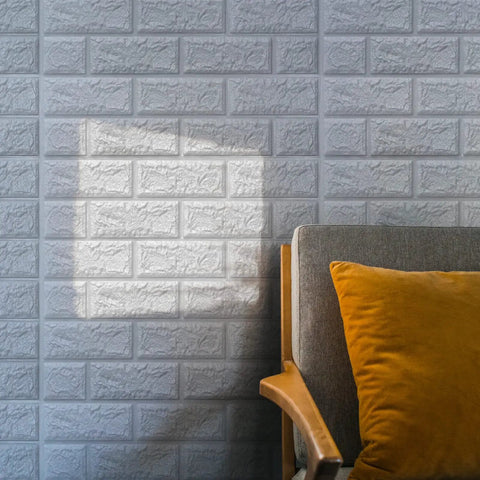 Peel And Stick 3D Foam Faux Brick Wall Panels White near an armchair with orange pillow, sunlight reflecting on the wall