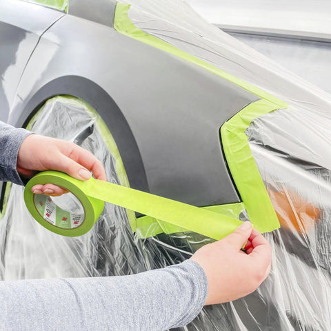 Person applying Pro Grade Three Quarters Inch Auto Paint Masking Tape, 55 Meter Green, UV and solvent resistant, on car trim