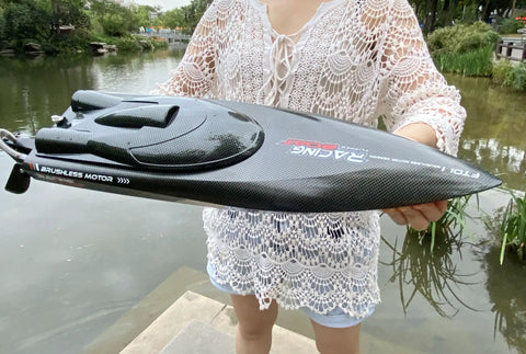 Person holding RTR 25.5 Inch Brushless Remote Control Boat With 2.4GHz Radio, 4WD Speed Watercraft, black waterproof hull