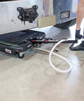 17 Gallon Low Profile Truck Drain With 120V Electric Pump For No Sweat Fluid Cleanup Features 6 Foot Discharge Hose Steel Hook and Heavy Duty Polypropylene Build For Weekend Warriors in use under truck.
