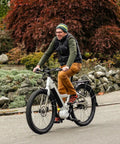 Person riding a bicycle on the road with autumn foliage in the background