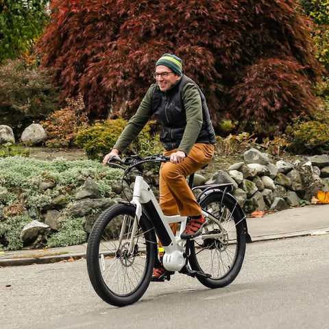 Person riding a bicycle on the road with autumn foliage in the background