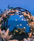 Tall Black Garden Arch Trellis 8.2 Ft High 6.2 Ft Wide Outdoor Arbor For Climbing Plants Roses And Vines Built To Last Perfect Lawn Wedding Archway Durable Weatherproof Construction decorated with flowers and lights at night by the sea