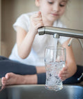 Child filling glass with water, illustrating use of Filtrasorb 200 Activated Carbon For Water And Air Filtration Refill 23 Lb
