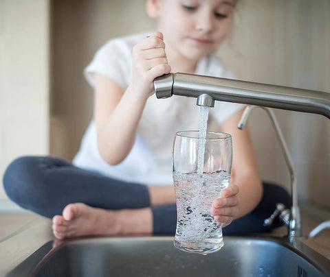 Child filling glass with water, illustrating use of Filtrasorb 200 Activated Carbon For Water And Air Filtration Refill 23 Lb
