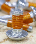 Close-up of VC-3 Threadmate Red Threadlocker And Tape Kit on threaded fastener, showing red coating on metal threads.