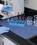 Lab workstation with blue adhesive-backed absorbent mat for industrial floors, 16 W x 25 Ft L, slip-resistant, easy cleanup.
