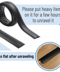 6 Ft Floor Cord Cover Cable Protector unrolled and laying flat, black PVC, shown on floor with instructions to unravel smoothly.