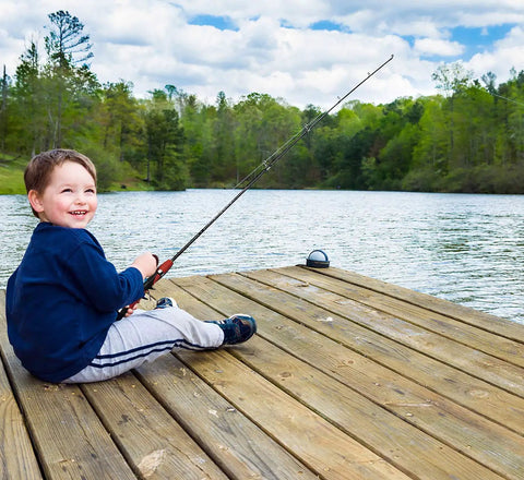 Child using Kids Telescopic Fishing Pole And Reel Combo With Tackle Box Easy Open Starter Kit by a lake on wooden dock
