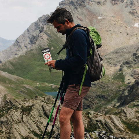 Hiker using Orienteering Compass For Hiking With Luminous Needle And Mirror on mountain path