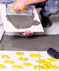 Massive 1600 Pack Plastic U Shaped Tile Spacers For Leveling Four Sizes In Black Yellow Red Blue One Sixteenth Inch One Eighth Inch Three Sixteenth Inch One Quarter Inch Great For DIY Tile Install scattered on floor during tile installation