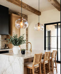 CASAMOTION Glass Pendant Lights, Textured Clear Globe Shade hanging above a kitchen island with wood beams and a marble countertop.